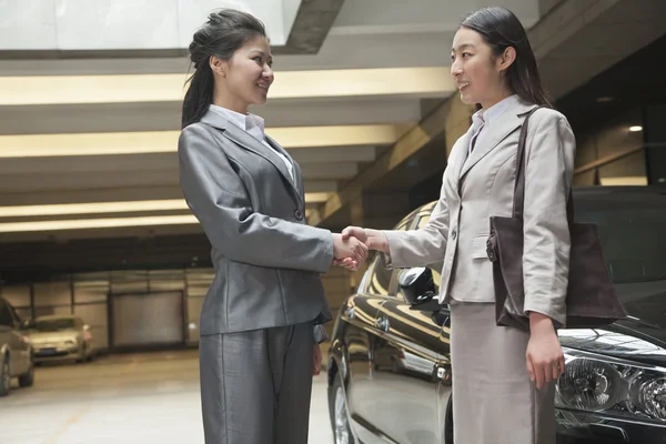 Businesswomen shaking hands in parking garage — Stock Photo, Image