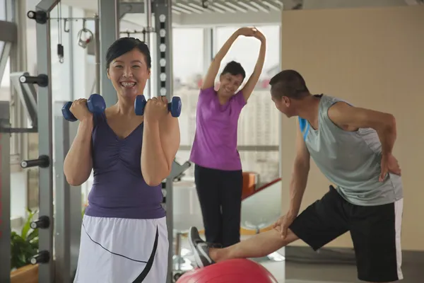 Woman lifting weights in the foreground — Stock Photo, Image