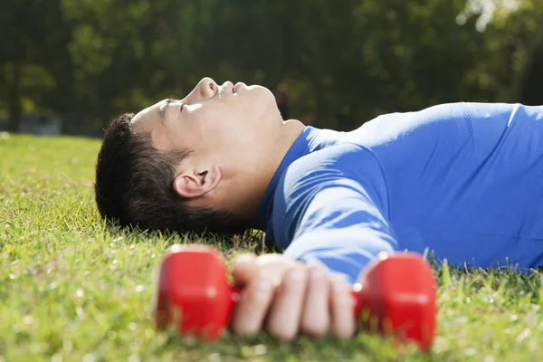 Atletik erkek dumbbells ile yatarken — Stok fotoğraf