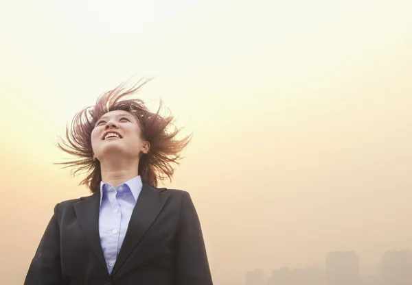 Businesswoman smiling with hair blowing — Stock Photo, Image