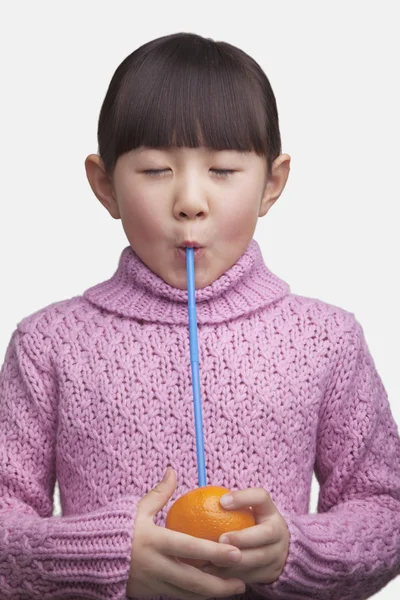 Girl drinking an orange with a straw — Stock Photo, Image