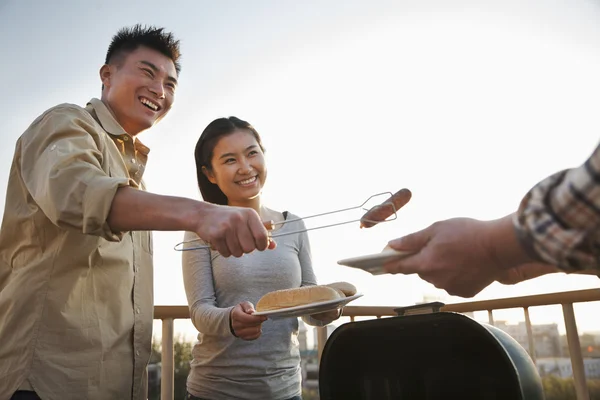 Hijo dando salchicha a su padre sobre la barbacoa — Foto de Stock