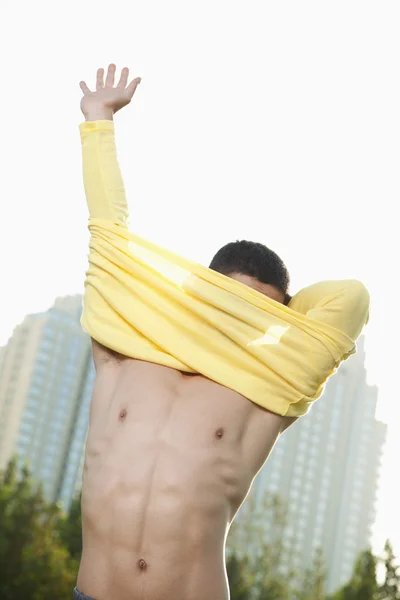 Hombre atlético quitándose la camisa en el parque — Foto de Stock