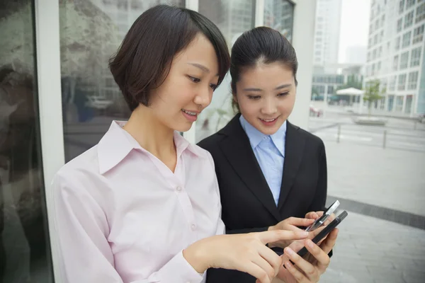 Vrouwelijke ondernemers op zoek naar hun mobiele telefoons — Stockfoto