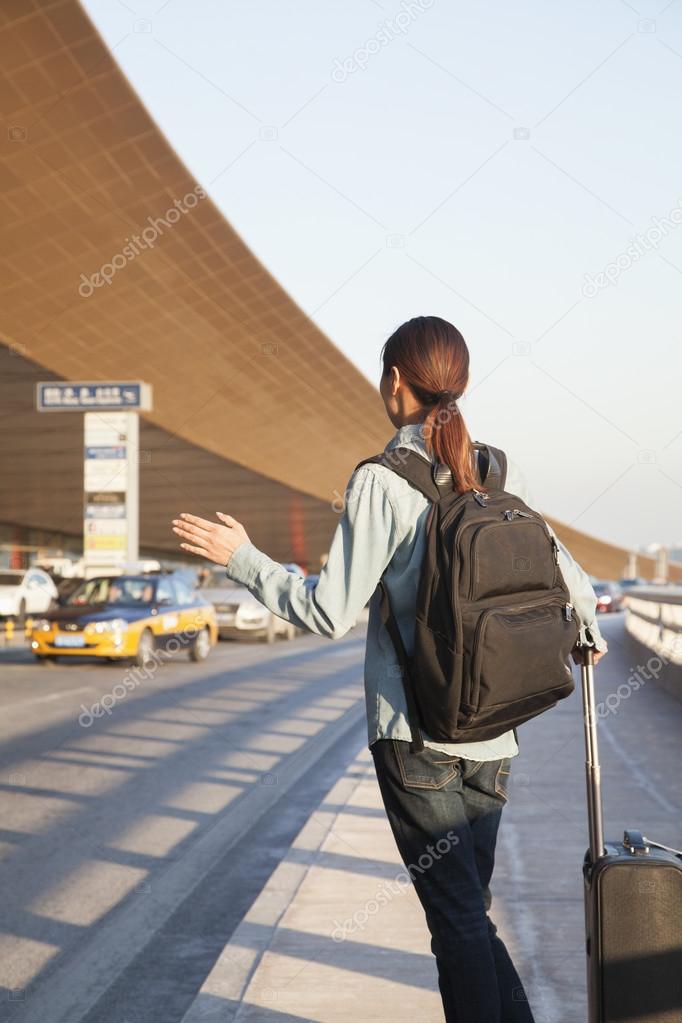 Traveler hailing a taxi at airport