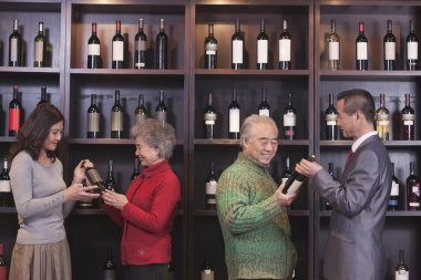 People Examining Wine Bottles at a Wine Store clipart