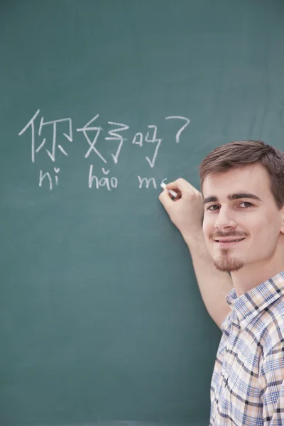 Teacher in front of chalkboard writing — Stock Photo, Image