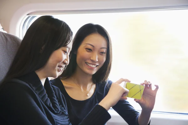 Ženy ve vlaku při pohledu na mobilní telefon — Stock fotografie