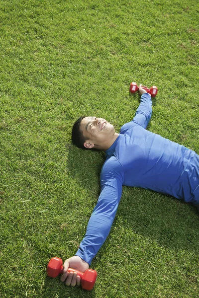 Athletic Man Lying Down in Park with Dumbbells — Stock Photo, Image