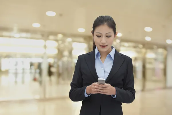 Businesswoman indoor texting on her phone — Stock Photo, Image