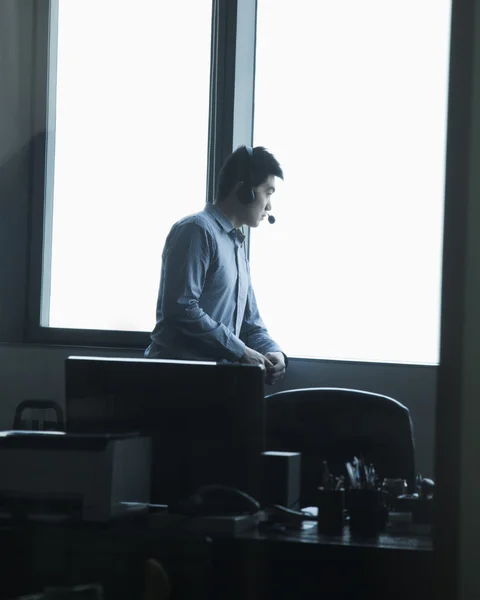 Homme regardant par la fenêtre dans le bureau — Photo