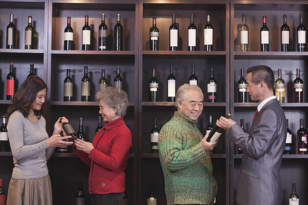 People Examining Wine Bottles at a Wine Store