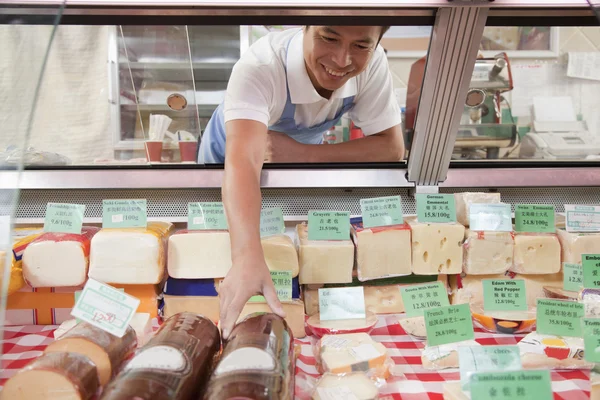 Sales Clerk reaching in to get cheese at Deli counter — Stock Photo, Image