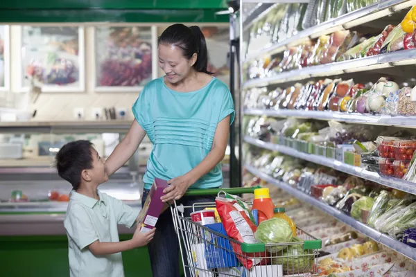 Moeder en zoon winkelen voor boodschappen in supermarkt — Stockfoto