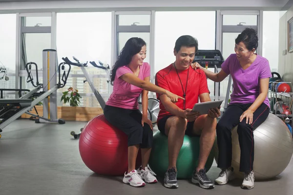 Les gens qui regardent tablette numérique dans la salle de gym — Photo