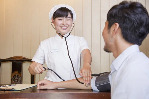 Krankenschwester überprüft den Blutdruck eines Geschäftsmannes — Stockfoto