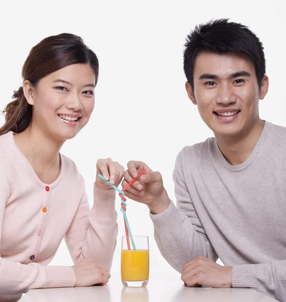 Couple sharing a glass of orange juice — Stok fotoğraf