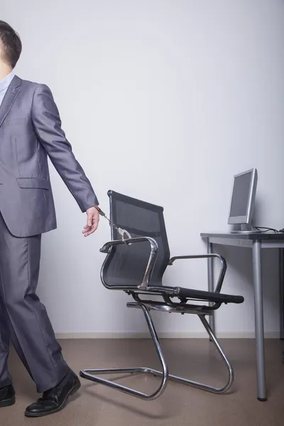 Businessman handcuffed to his office chair — Stock Photo, Image