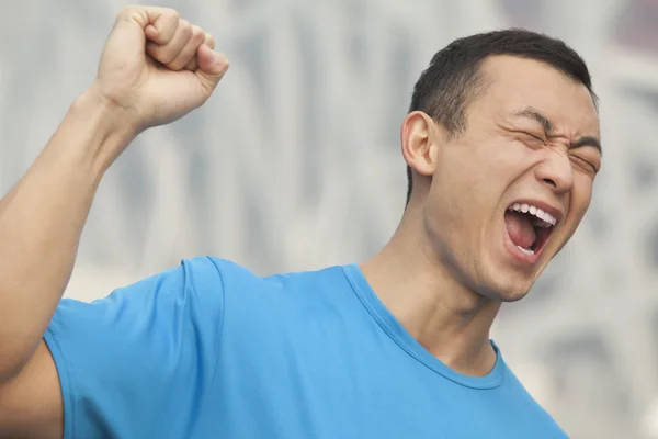 Homem de t-shirt azul com punho levantado no ar — Fotografia de Stock