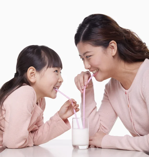 Mother and daughter sharing a glass of milk — Stock Photo, Image