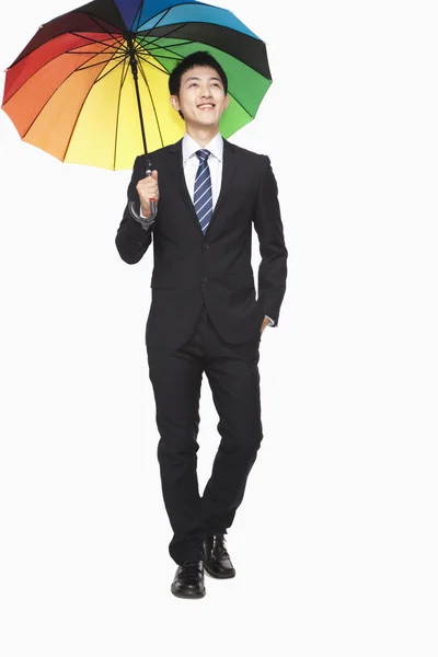 Businessman walking with colorful umbrella — Stock Photo, Image