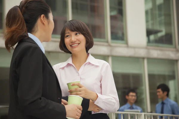 Businesswomen talking and drinking coffee outdoors — Stock Photo, Image