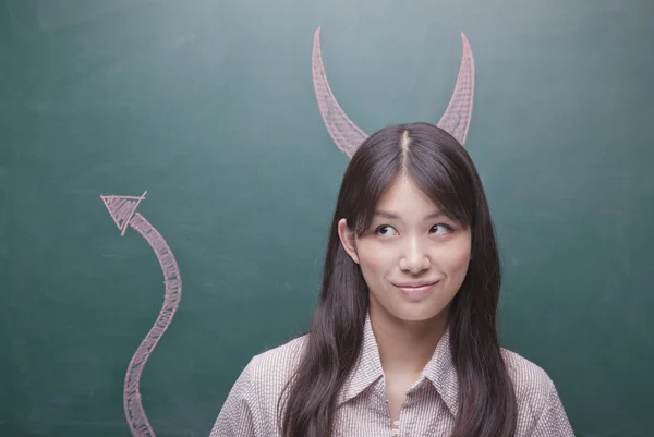 Kvinna med djävulens horn och svans på blackboard — Stockfoto