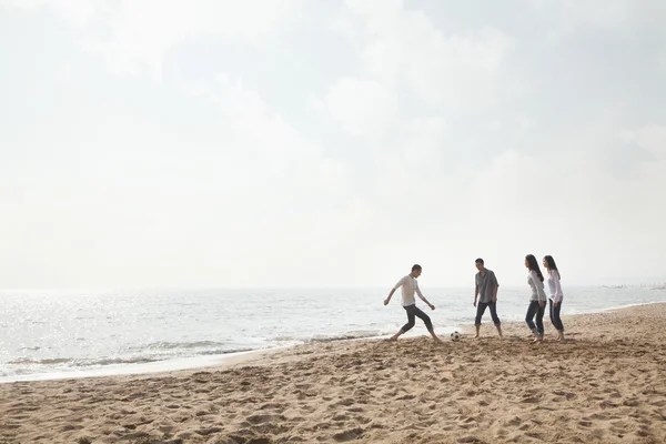 Přáteli, kteří hrají fotbal na pláži — Stock fotografie