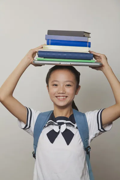 Κοπέλα που κρατά μάτσο φορητούς υπολογιστές και φορητό υπολογιστή στο κεφάλι της — Φωτογραφία Αρχείου
