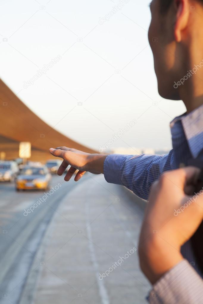 Traveler hailing a taxi outside of the airport