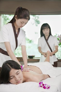 Two Masseuses Massaging One Woman clipart