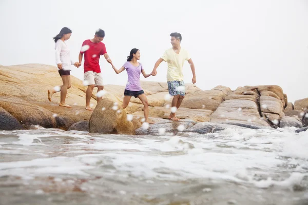 Amigos caminando sobre rocas junto al mar —  Fotos de Stock