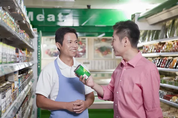 Sales clerk assisting man in supermarket — Stock Photo, Image