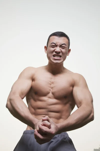 Muscular hombre gruñendo y flexión sin camisa — Foto de Stock