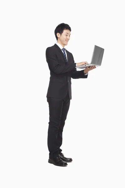 Empresario usando portátil mientras está de pie —  Fotos de Stock