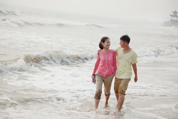 Couple marchant au bord de l'eau sur la plage — Photo