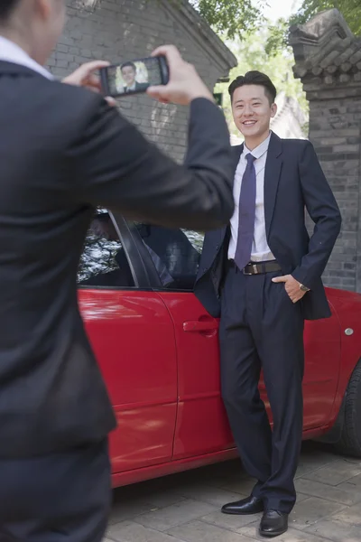 Businesswoman Taking Businessman's Picture Next to His Car — Stock Photo, Image