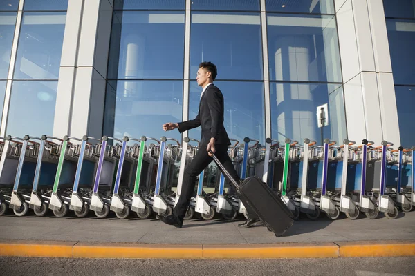 Traveler walking fast next to row of luggage carts — Stock Photo, Image