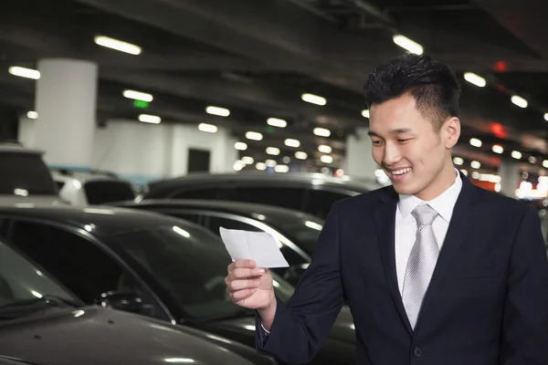 Traveler looking at ticket in airport parking lot — Stock Photo, Image