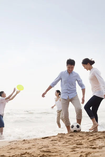 Mensen spelen voetbal en frisbee op het strand — Stockfoto