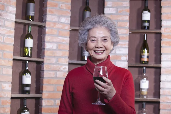 Seniorin hält Glas Wein in der Hand — Stockfoto