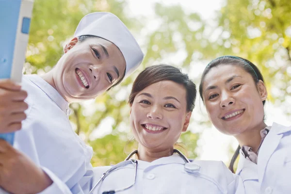 Drie artsen kijken neer op camera — Stockfoto