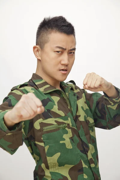 Man in military uniform putting up fists to fight