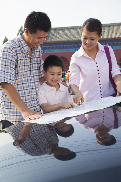 Family standing next to the car and looking at the map — Stock Photo, Image