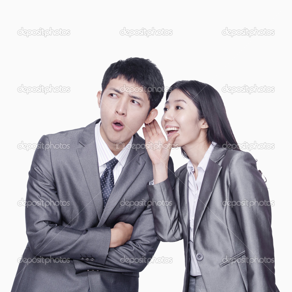 Businesswoman whispering in businessman's ear