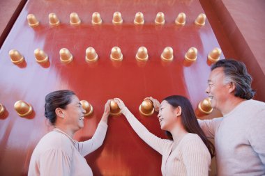 Granddaughter with grandparents standing next to the traditional red doors clipart