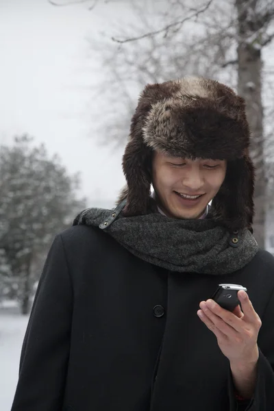 Homme en chapeau de fourrure regardant le téléphone portable — Photo