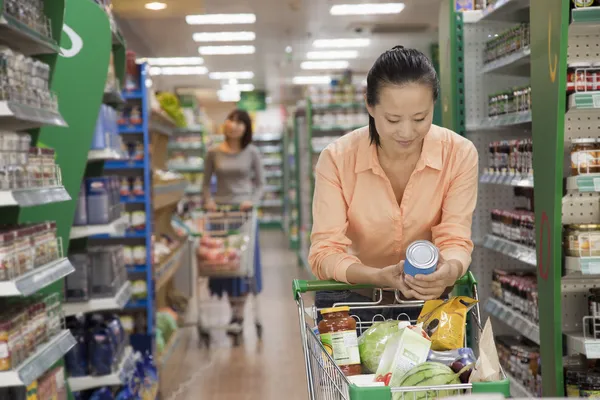Frau liest Dose im Supermarkt — Stockfoto