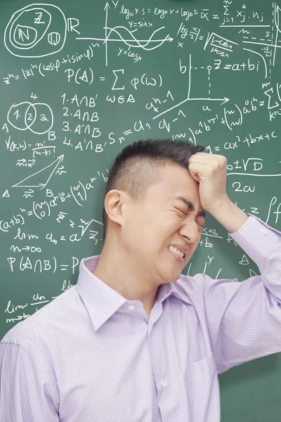 Frustrated young student in front of blackboard — Stock Photo, Image