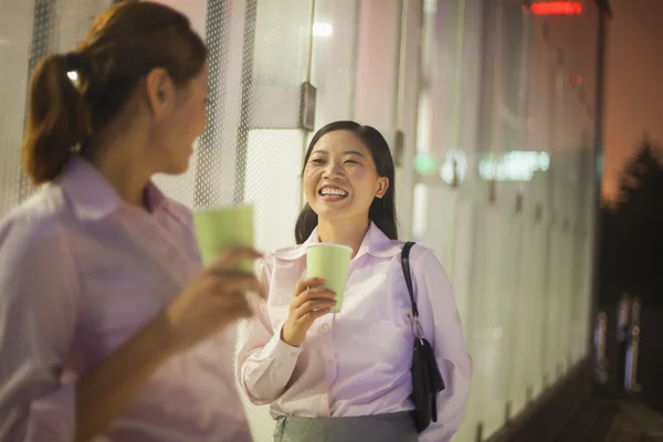 Деловые женщины улыбаются и пьют кофе на открытом воздухе — стоковое фото
